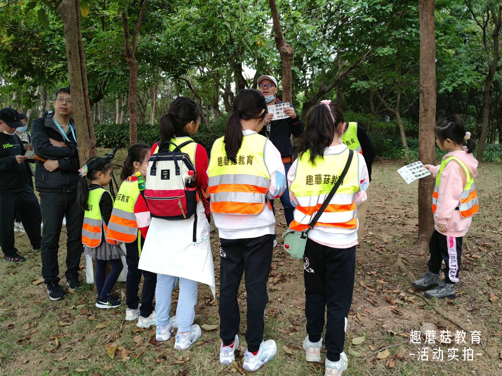 The group in orange vests walking through the park