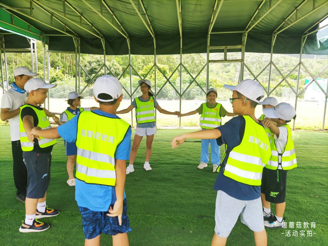 Campers in green vests cheering on the field